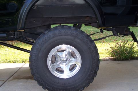 2000 Ford F-150 - Close-up of a vehicle's rear wheel assembly, showing off-road tire and suspension components.