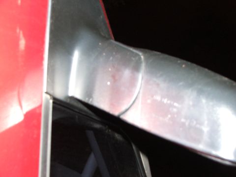2003 Ford Sport Trac - Close-up of the edge of a red vehicle door and its chrome trim, with a watermark for Supermotors.net visible.
