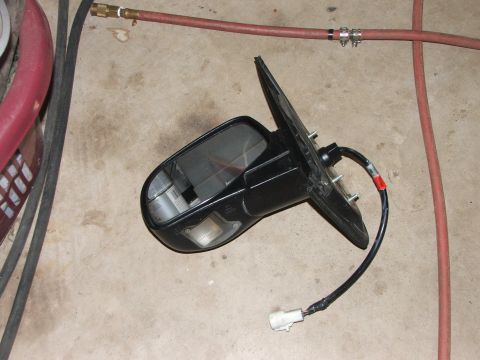 2003 Ford Sport Trac - Side mirror assembly removed from a vehicle, lying on a concrete floor.