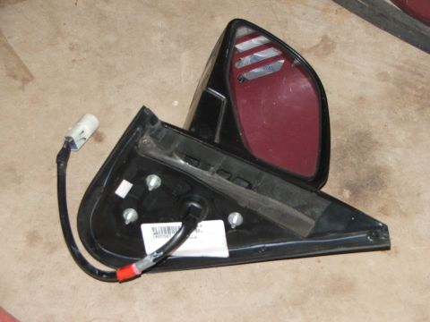 2003 Ford Sport Trac - A detached car side mirror lies on a concrete surface, showing its internal components and wiring.