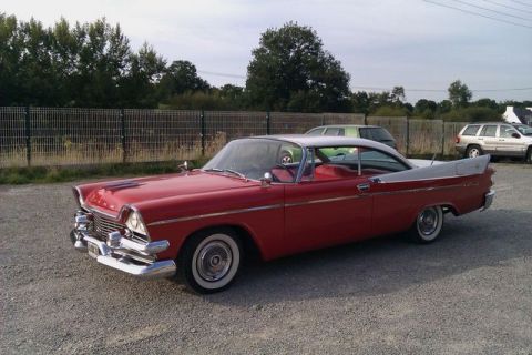 1991 Ford Crown Victoria - A classic red and white 1957 Dodge Custom Royal coupe is parked outdoors.