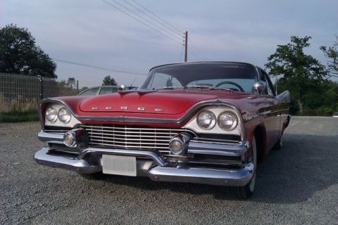 1991 Ford Crown Victoria - This red vintage car has a distinctive chrome grille and dual headlights, suggesting a mid-20th-century model.