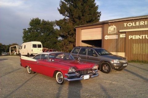 1991 Ford Crown Victoria - A red and white 1959 Dodge Custom Royal Lancer coupe is parked in front of a building with a grey Jeep Grand Cherokee beside it.