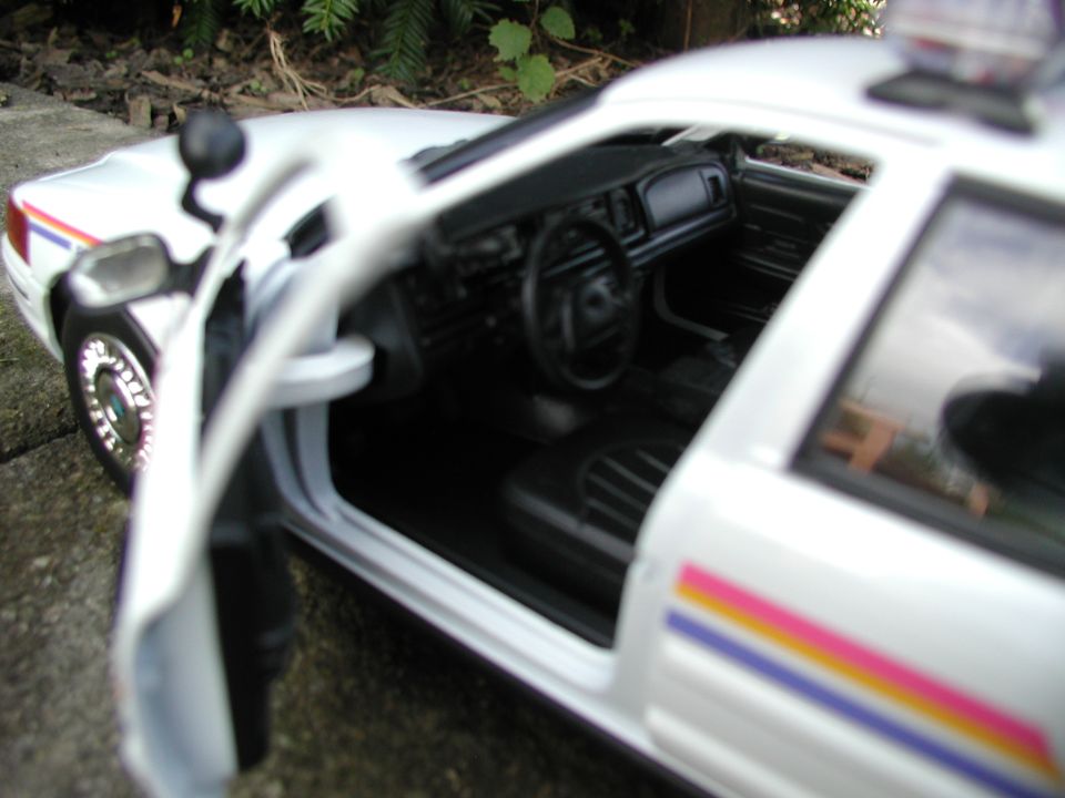 White police car model interior with open door, black seats, dashboard, and steering wheel