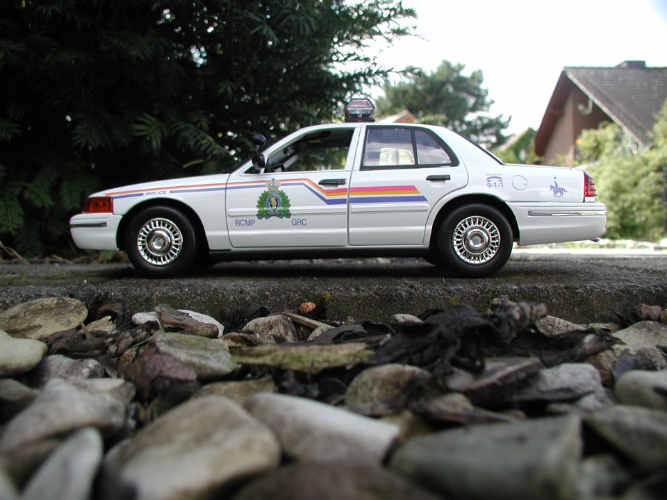 Model police car with RCMP markings, parked on a rocky surface