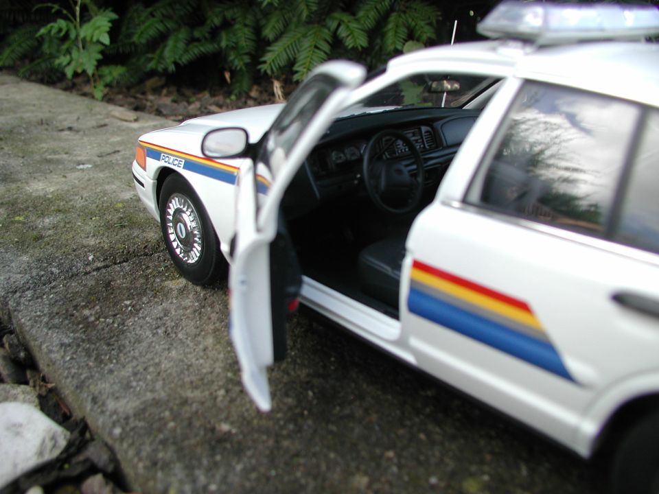 White die-cast model police car with driver door open showing molded interior