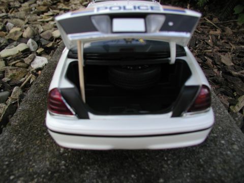 2001 Audi A4 - The trunk of a white police car is open, showing a spare tire and a wooden prop rod holding the trunk lid up.