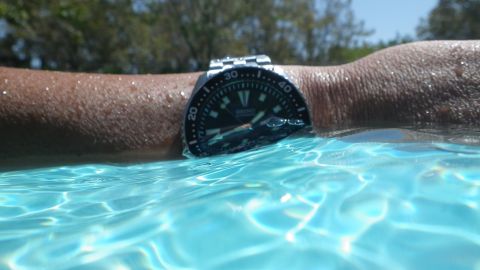 1996 Ford Bronco - Watch on arm in pool water, with trees in background.