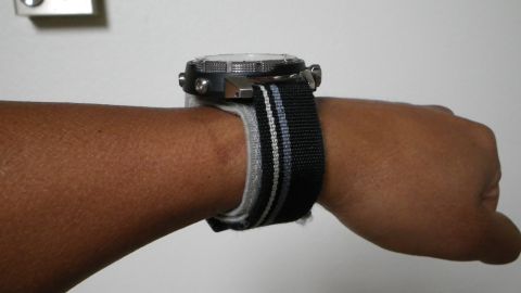 1996 Ford Bronco - A watch with a black and grey striped band is worn on a wrist.