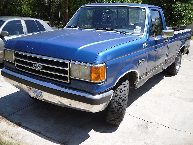 Blue Ford F-150 regular-cab pickup with bed toolbox parked in a driveway