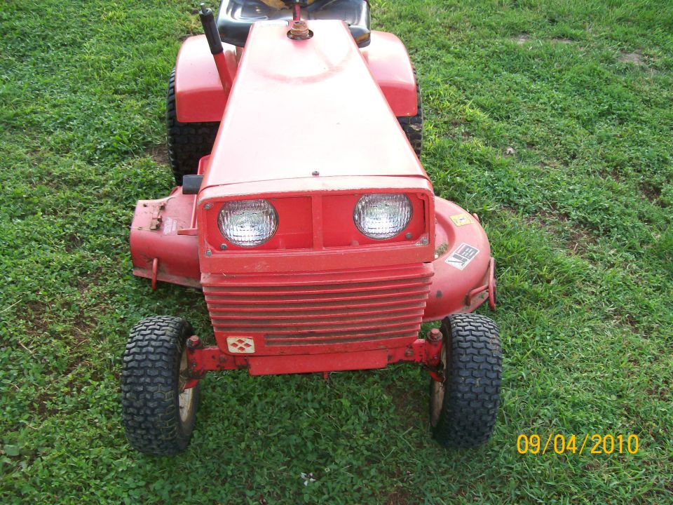 Front view of red riding lawn tractor with dual headlights on grass