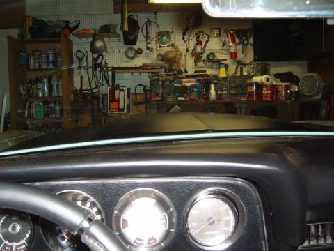 1973 Ford Ranchero - The dashboard and steering wheel are visible in the foreground, with a workshop area in the background.