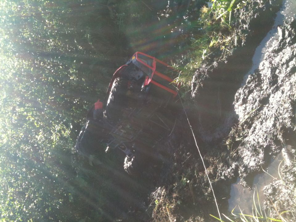 ATV stuck in mud with a red roll cage visible