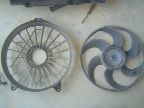 1994 Ford Crown Victoria - Two parts of a car's cooling system, a fan and its shroud, are shown disassembled.