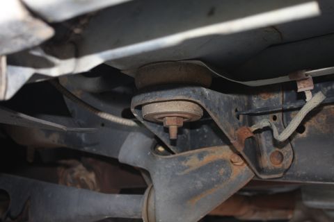 1990 Ford F-150 - Undercarriage view of rusty frame and suspension parts, including a rubber mount.