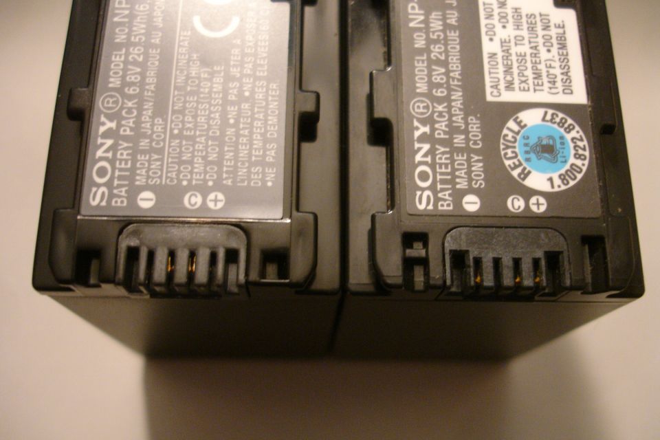 Two Sony NP-F970 battery packs shown up close, detailing their connectors and labels
