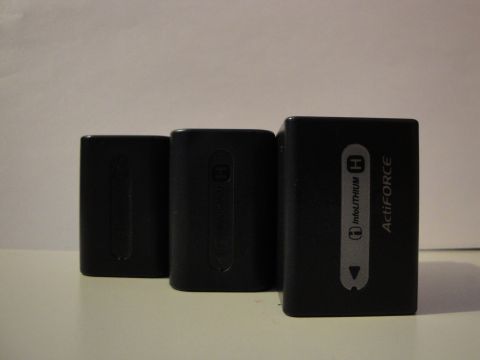 1993 Ford Taurus - Three black camera batteries are lined up on a white surface against a plain background.