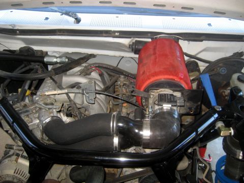 1996 Ford Bronco - The engine bay of a 1996 Ford Bronco shows a red aftermarket air filter and custom intake piping.