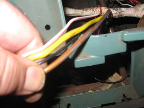 1981 Ford Bronco - A close-up shows a hand manipulating a cluster of electrical wires within a vehicle's interior.