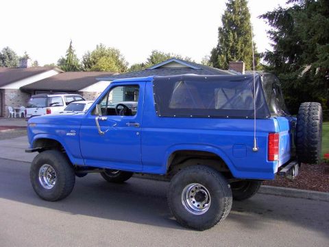 1980 Ford Bronco - This blue Ford Bronco features a removable soft top and is lifted with off-road tires.