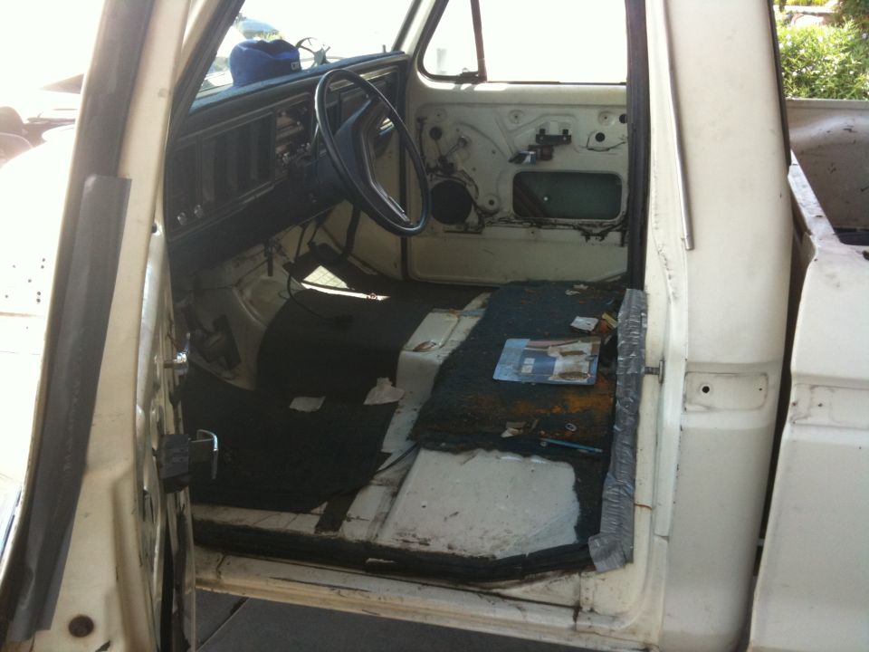 Interior of a white pickup truck with doors open, showing the dashboard, steering wheel, and floor