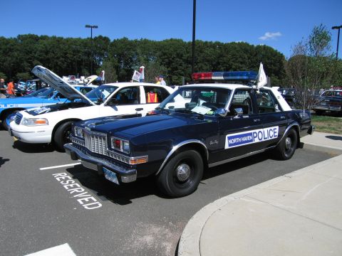 1991 Ford LTD Crown Victoria - dark-blue sedan marked NORTH HAVEN POLICE with a roof light bar is parked in a RESERVED show spot beside other patrol cars.