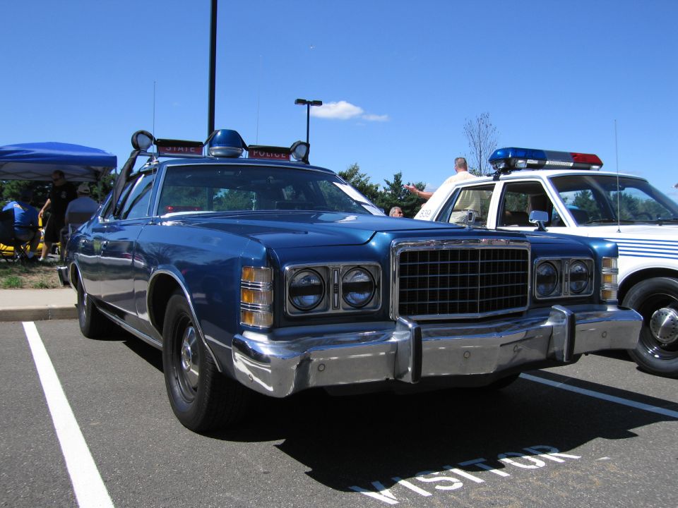Blue 1970s Ford LTD police car with roof spotlight and light bar
