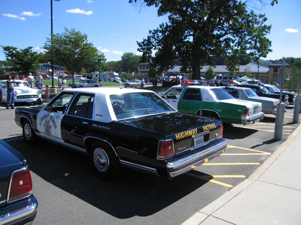 Rear of black and white Highway Patrol Ford sedan at a car show