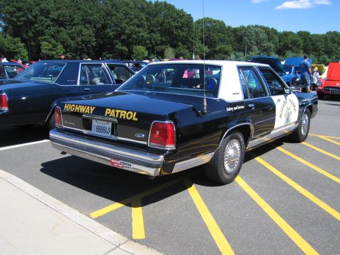 1991 Ford LTD Crown Victoria - Rear view of a black-and-white Highway Patrol Ford Crown Victoria sedan with wire wheel covers at a show.