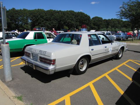 1991 Ford LTD Crown Victoria - Rear three-quarter view of a white State Police sedan with roof light parked at an outdoor car show.