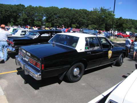 1991 Ford LTD Crown Victoria - Rear three-quarter view of a black-and-white police Chevrolet sedan with white roof parked at a show.