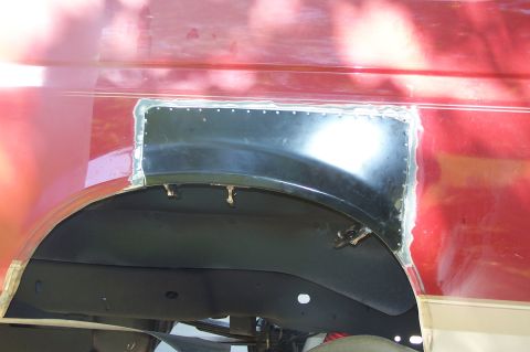 1990 Ford Bronco - A red vehicle's rear wheel well area shows a newly riveted metal patch, indicating body repair.