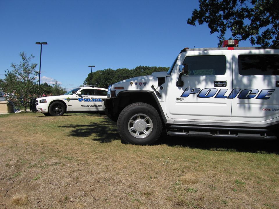 White Police Hummer H2 beside a Dodge Charger cruiser on grass