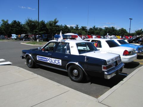 1991 Ford LTD Crown Victoria - black and white vintage four-door police sedan marked 'North Haven Police' number 41 with a roof light bar, parked among other cars.