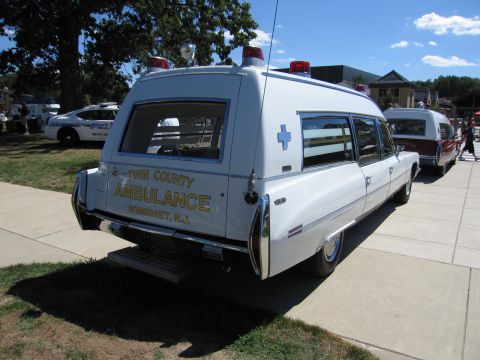 1991 Ford LTD Crown Victoria - white Cadillac-based ambulance lettered 'Twin County Ambulance, Somerset N.J.' with roof beacons, displayed on grass at a show.