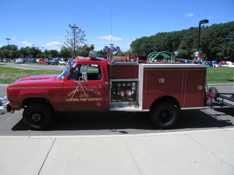 1991 Ford LTD Crown Victoria - red 4x4 fire truck lettered 'Central Fire Co, Central Fire District' with hoses and equipment, parked on pavement at an outdoor show.