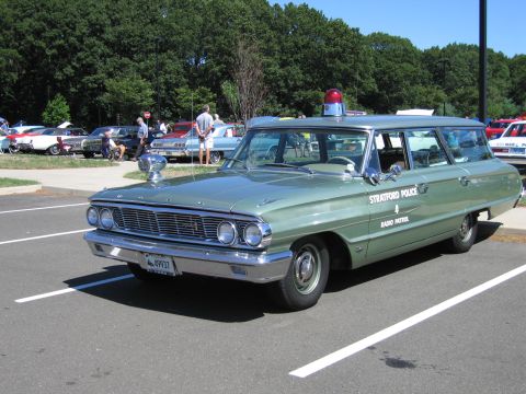 1991 Ford LTD Crown Victoria - green early-1960s Ford full-size station wagon lettered 'Stratford Police Radio Patrol' with a single roof beacon, parked at a show.