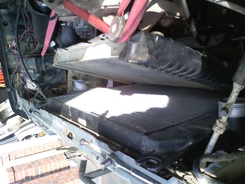 1990 Ford Bronco - Close-up of a radiator installation in progress, showing the engine bay components and straps.