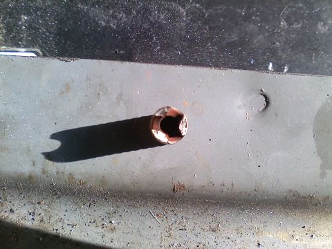 1990 Ford Bronco - Detail of a corroded bolt hole on a vehicle's metal body panel.