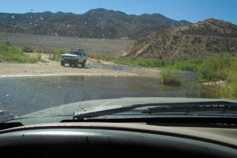 1995 Ford Bronco - White 1995 Ford Bronco navigates a shallow stream in a desert landscape.