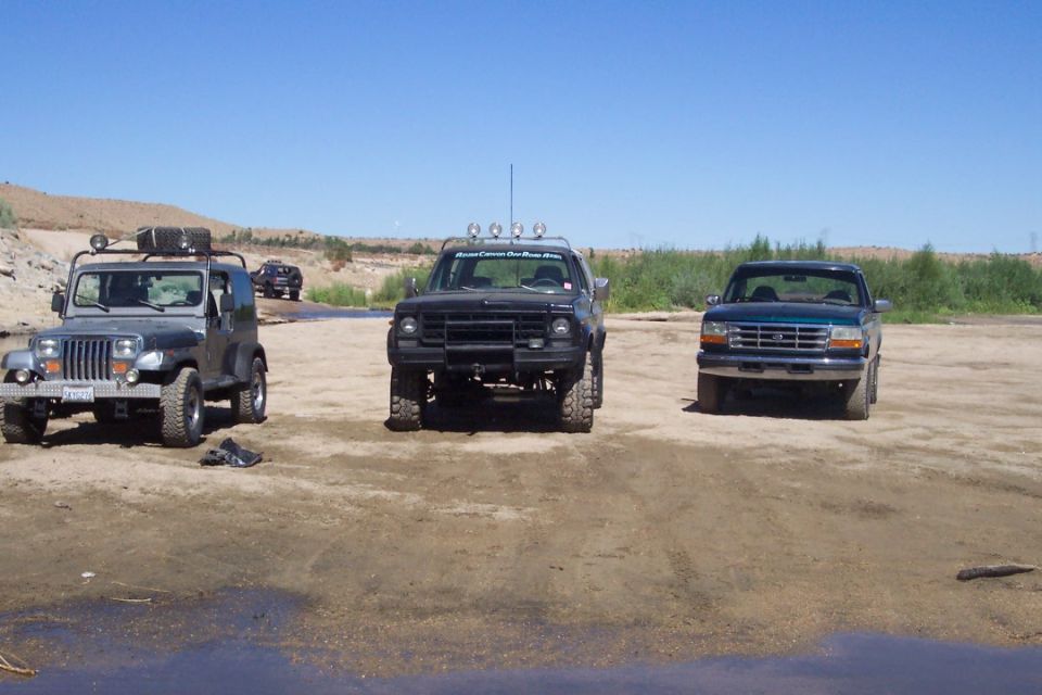 Jeep Wrangler, Ford F-150, and Ford Bronco parked on dirt