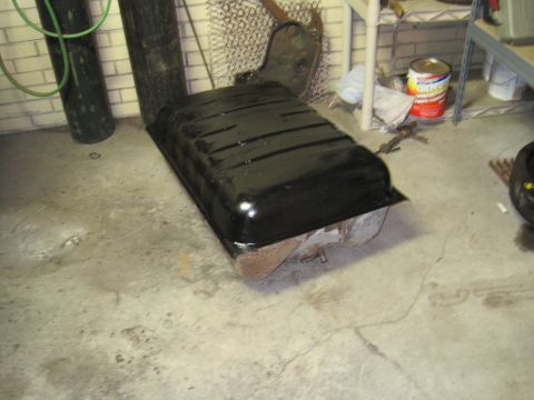 1979 Ford Bronco - A black fuel tank, possibly for a vehicle, rests on a concrete floor in what appears to be a garage or workshop.