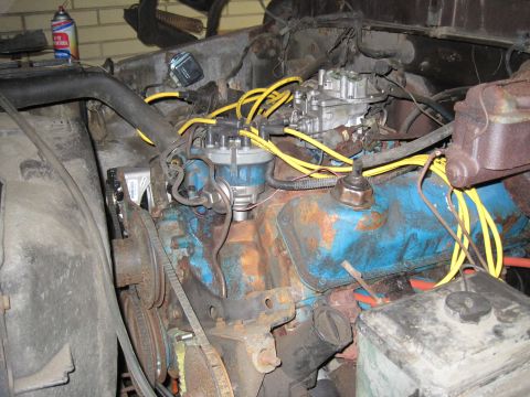 1979 Ford Bronco - Close-up view of a vehicle's engine bay, a blue engine block, carburetor, and yellow spark plug wires.