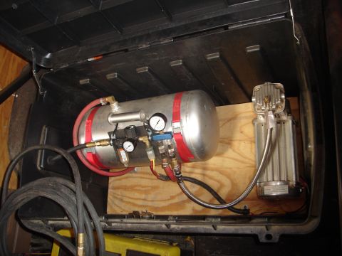 1989 Ford Bronco - An onboard air system with a silver tank and compressor is visible within a dark compartment.