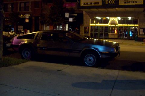 1998 Dodge Viper - A DeLorean DMC-12 is parked on a city street at night in front of a movie theater.