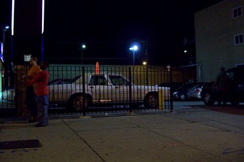 1998 Dodge Viper - White pickup truck with an orange cone on the roof, parked behind a fence at night.