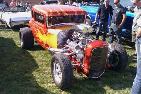 1991 Ford Crown Victoria - A custom hot rod with a prominent engine and flame paint job is displayed outdoors with spectators nearby.