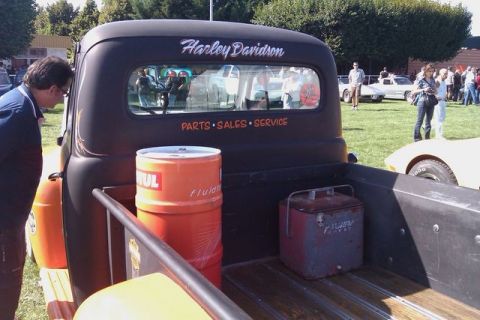 1991 Ford Crown Victoria - A vintage pickup truck with "Harley Davidson" and "Parts Sales Service" text on its rear window is parked on a grassy field.