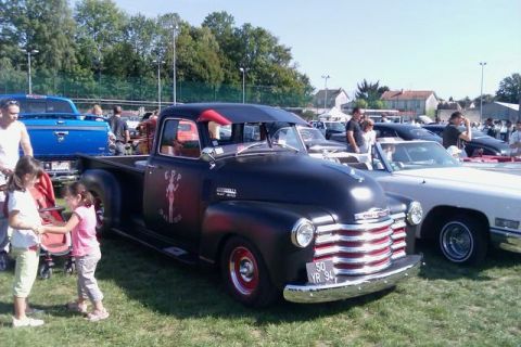 1991 Ford Crown Victoria - A vintage Chevrolet pickup truck is displayed at an outdoor car show alongside other vehicles.
