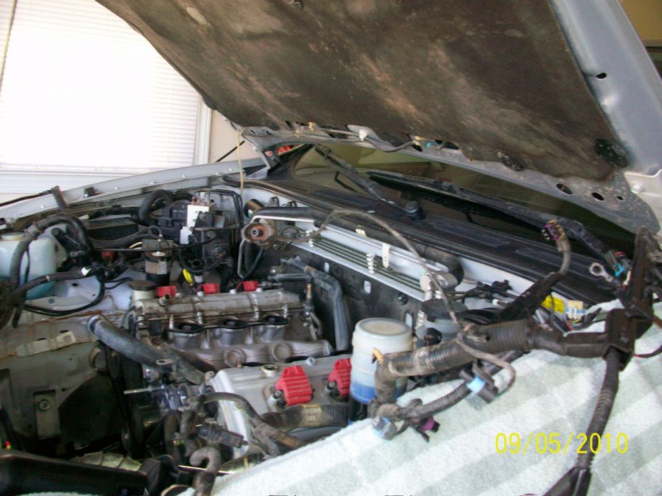 Engine bay with hood open, showing engine components and wiring harnesses. A date stamp reads 09/05/2010
